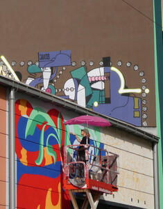 At top, an abstract painting. At bottom, an artist working on a painting that is also abstract in bright colors