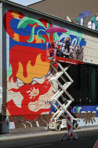 Artist on hydraulic lift, painting top of wall