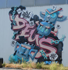 Tag: DEUS; near a totem pole with a skull in middle and owl on top.