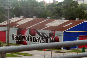 Wall of buildilng showing man in boxing gear punching a bag. Text: Hard work pays off