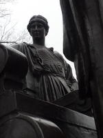 Closeup of man standing to right behind Alma Mater