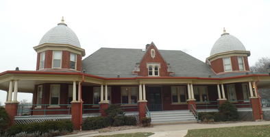 Building with large porch and two domes on top of second floor at either side.