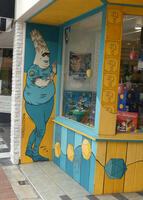 Front of game store with painiting of alien in a t-shirt with dice on the sleeve