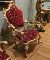 Red stuffed armchari with gold scrollwork on arms and back
