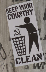 Silhouette of man throwing hammer and sickle in garbage can. Text: keep your country clean