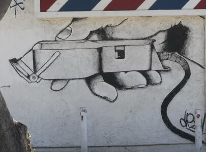Wall painting on front of barber shop showing hand holding electric razor
