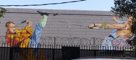 Wall art showing one martial artist kicking high and another with a sword