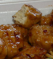 Vegan orange chicken from Panda Express; shows several chicken nuggets, with one bitten into to show texture