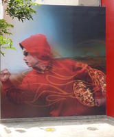 Person in red hoodie running with pizza under arm.