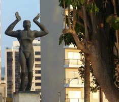 Statue of man with arms upraised as though pushing something upwards