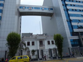 Old building between two large modern buildings with walkway between them