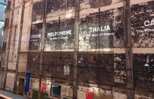 Names of muses (Terpsichore, Melpomene, Thalia) painted on brick wall