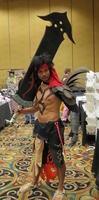 man in red cape, carrying huge sword-like weapon