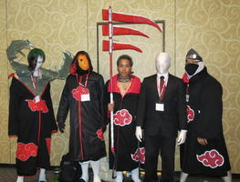 Group of warriors surrounding man in white body suit who is wearing a business suit