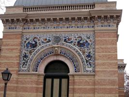 Colored tiles with bird motif on side of brown brick building