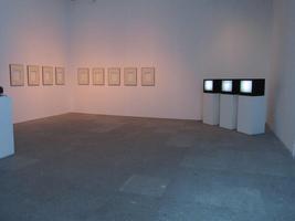 Room showing multiple small blank picture frames and three television sets with “snow”