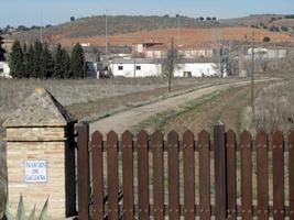 Farmland near train station; brown wooden picket fence in foreground