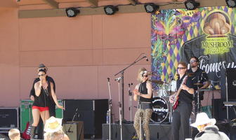 Performers on stage; woman performer in black tank top and red shorts.