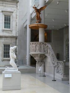 Staircase with relief figures carved on side; bronze statue of angel above