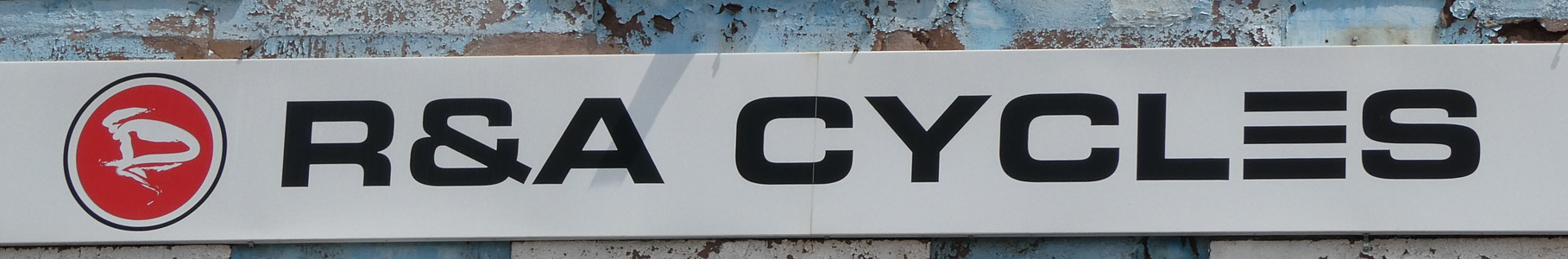 Sign for R & A Cycles with logo in form of a stylized bicycle rider in racing helmet