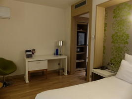 edge of bed in foreground, desk in background