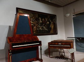Piano with strings mounted vertically in trapezoidal box