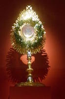 Artifact in shape of teardrop; crystal in center and green jewels around