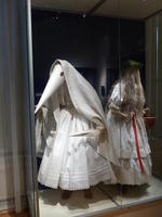 Figure in white dress, wearing conical mask