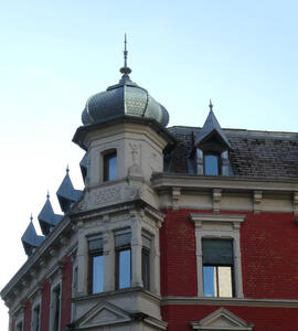 Onion dome roof at corner, at intervals there are sharply angled small “roofs” above windows.