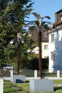 Metal sculptured palm trees with silver leaves and rust-colored tree trunks.