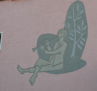 Wall painting of a barefoot man playing a flute. he is seated beneath a tree.