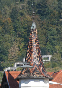 Spire of church with brown and black shingles in a geometric pattern
