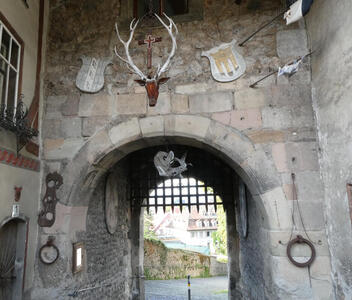 Stone archway with stag head above the arch; coat of arms to left and right of head. An open portcullis is in the arch.