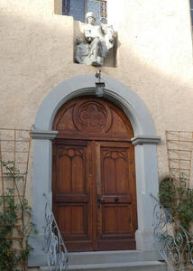 Carved wooden door. Above it, a religious sculpture.