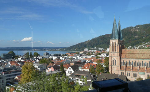 View of city; church at right, city buildings in midground, lake in background.