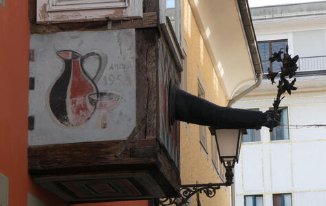 Metal sculpture of an arm holding a bunch of flowers. The sculpture protrudes from the wall of a building.