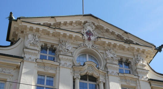 Ornate carvings at top of building. A shield shows an eagle in red.