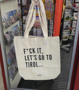 Cream-coloured canvas shopping bag with black lettering: F*CK IT, LET’S GO TO TIROL...