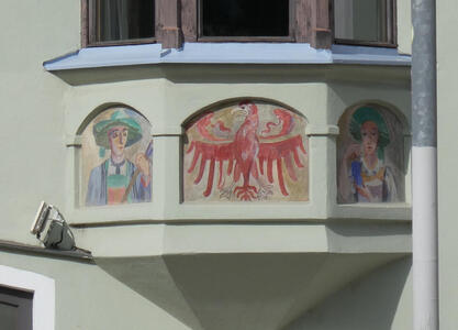 In middle, a red eagle. At left and right, a male and female farmer in traditional garb.
