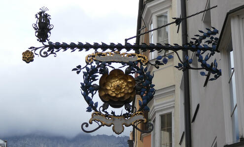 Metalwork sign; in middle a gold flower.
