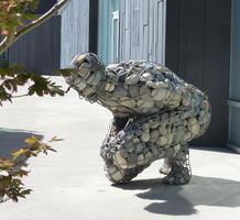 Rock-filled wire frame sculpture of a crouching man.