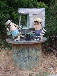 Two men in front of camper; one has flashlight for nose.