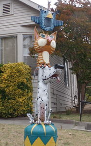 Totem pole with blue bird, striped orange cat, and dalmation (from top to bottom)