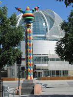 Column with diamonds on surface and “futuristic antennae” on top; San Jose City Hall in background.