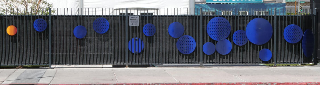 Multiple blue circles  of varying sizes attached to a fance; at left, one small orange circle