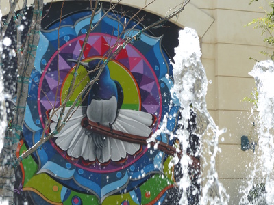 Wall art of blue and white bird in background; fountain in foreground.