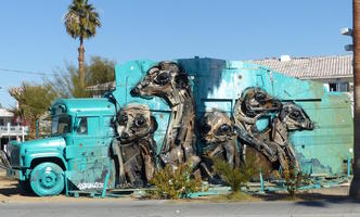 Meerkats sculptured onto side of aqua-colored bus.