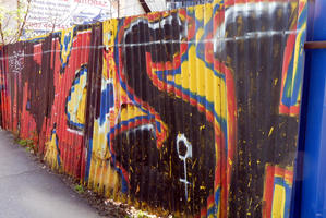 Multi-colored large letters on corrugated metal fence