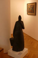 Sculpture of woman with hood carrying bucket.