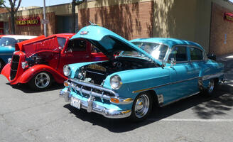 Blue sedan in foreground, red roadster in background